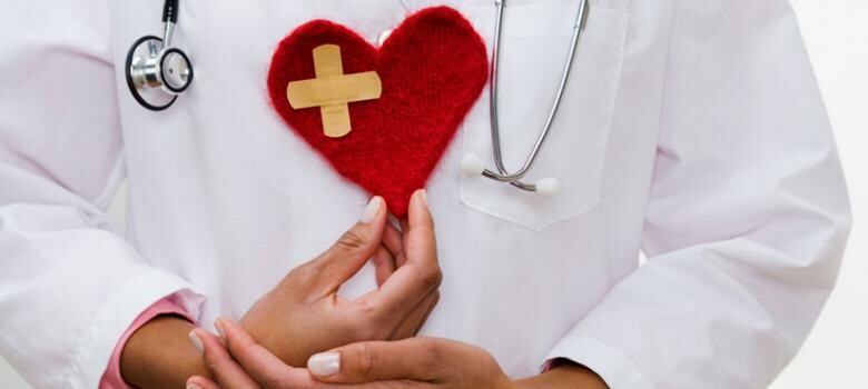 Doctor holding a decorative heart made of red felt fabric
